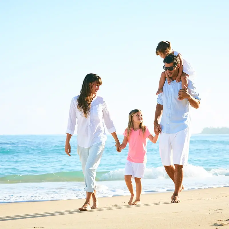 A family walking on the beach holding hands.