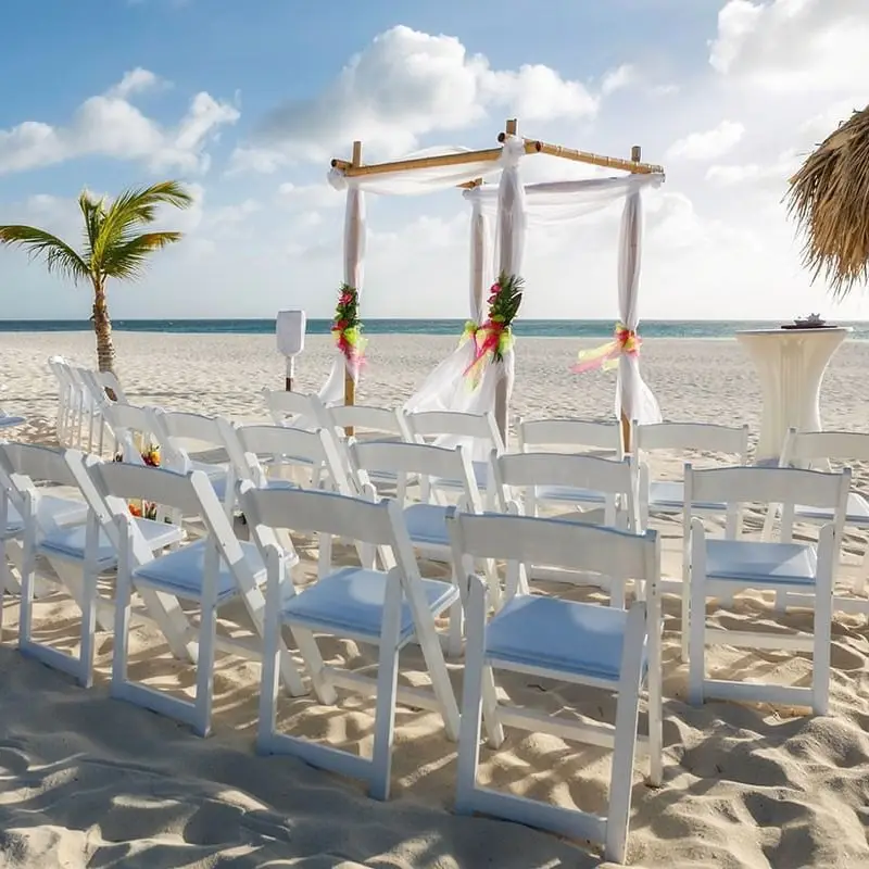 A beach with chairs and tables set up for an outdoor wedding.