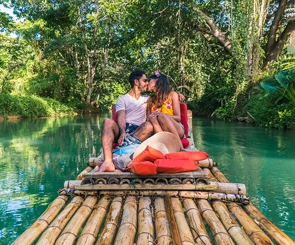 A couple is sitting on the raft in the water.