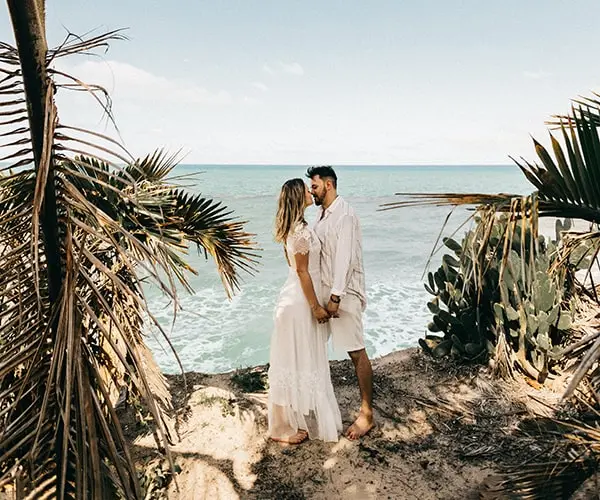 A man and woman standing on top of a beach.