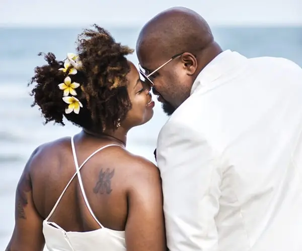 A man and woman kissing on the beach.