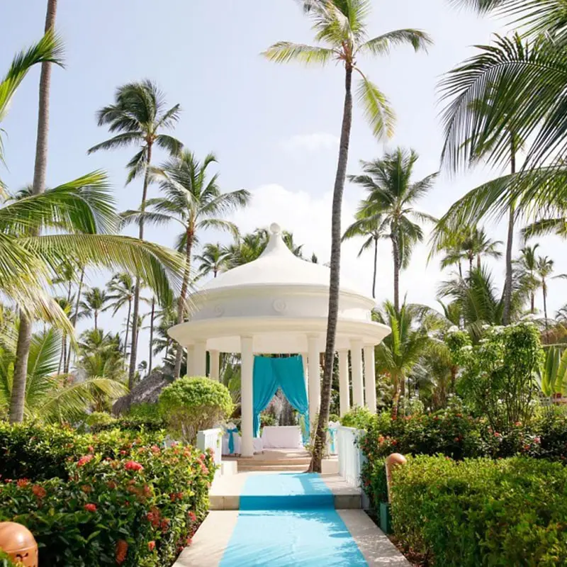 A gazebo with palm trees and bushes around it