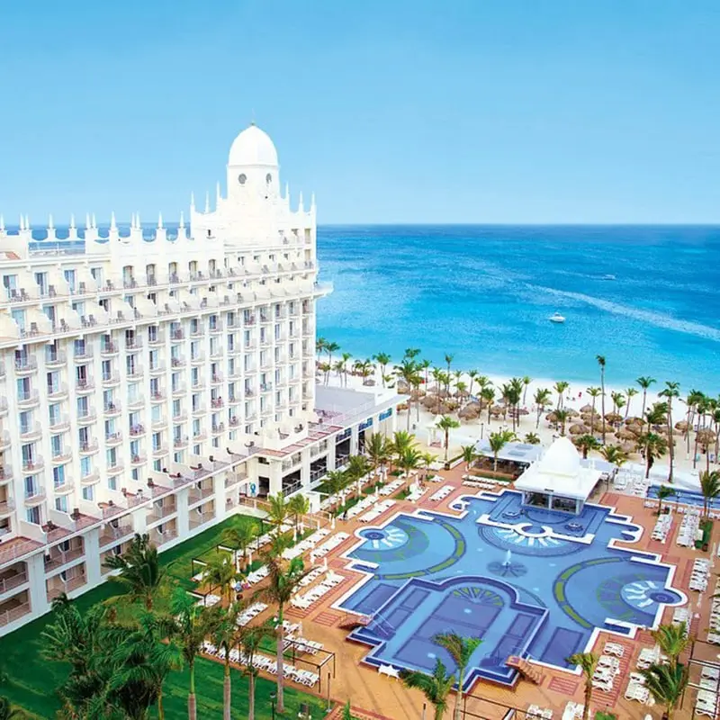 A large white building with pools in front of it.