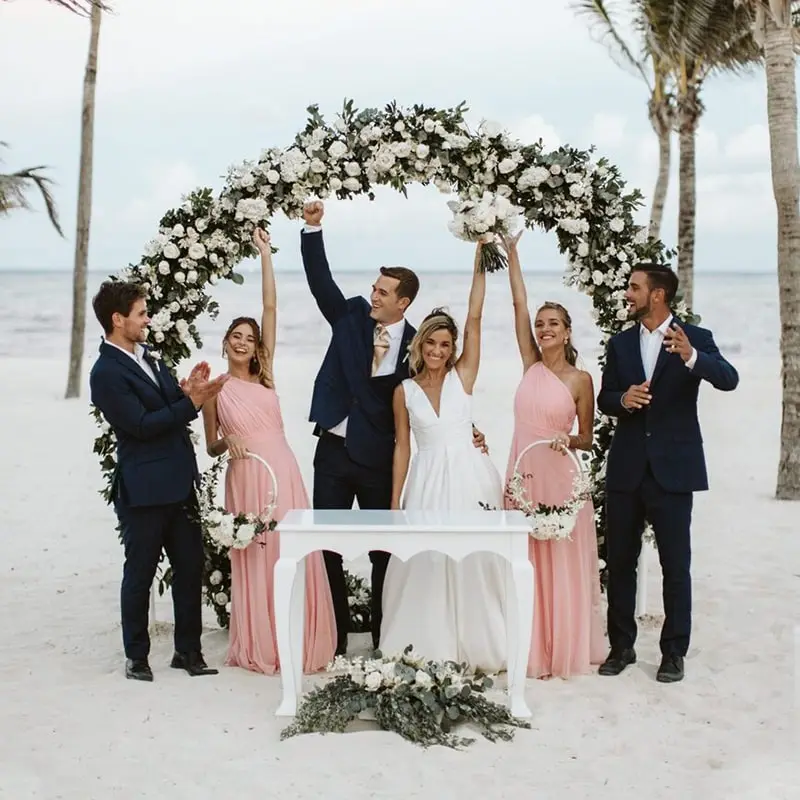 A group of people standing around a table on the beach.