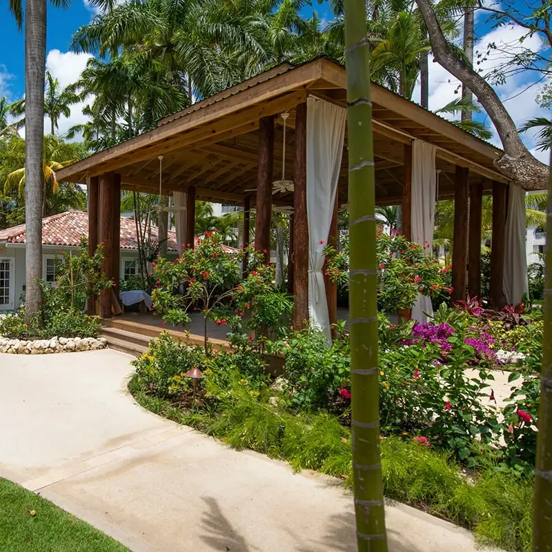 A gazebo with flowers and trees in the background.