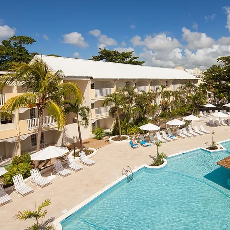 A pool with chairs and umbrellas in the background.