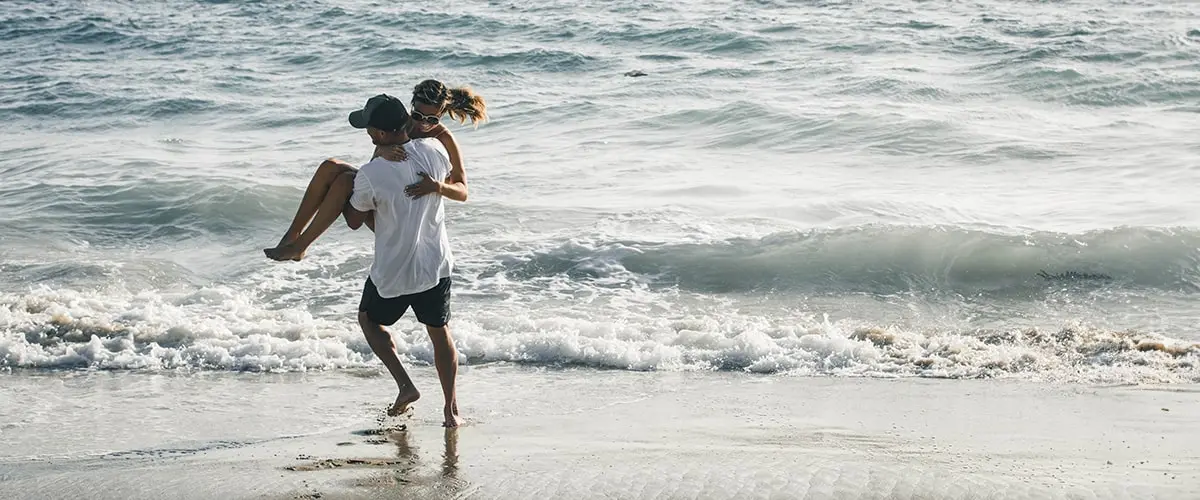 A man and woman running on the beach.