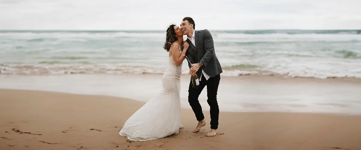 A man and woman kissing on the beach.