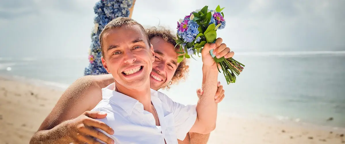 Two men holding flowers and smiling for the camera.