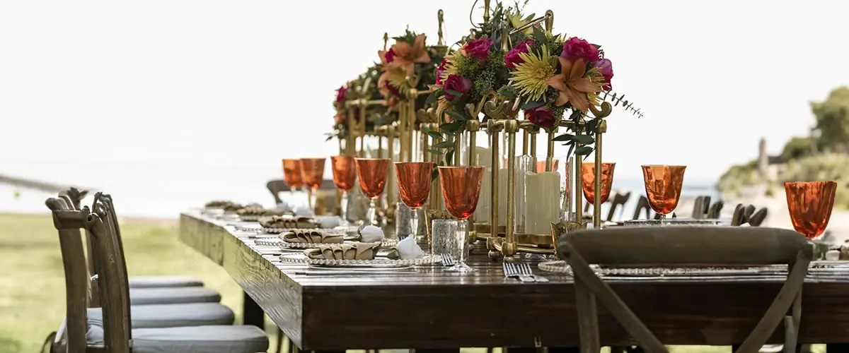 A long table with many glasses and flowers