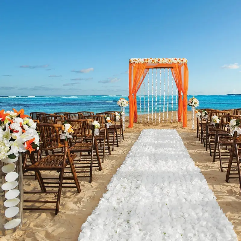 A beach wedding with orange and white flowers.