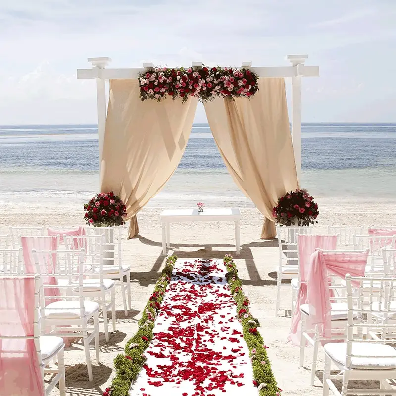 A wedding ceremony on the beach with flowers and chairs.