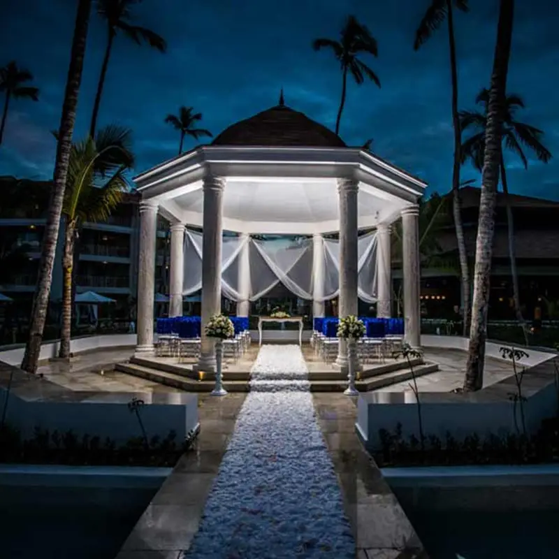 A gazebo with blue chairs and umbrellas in the middle of it.