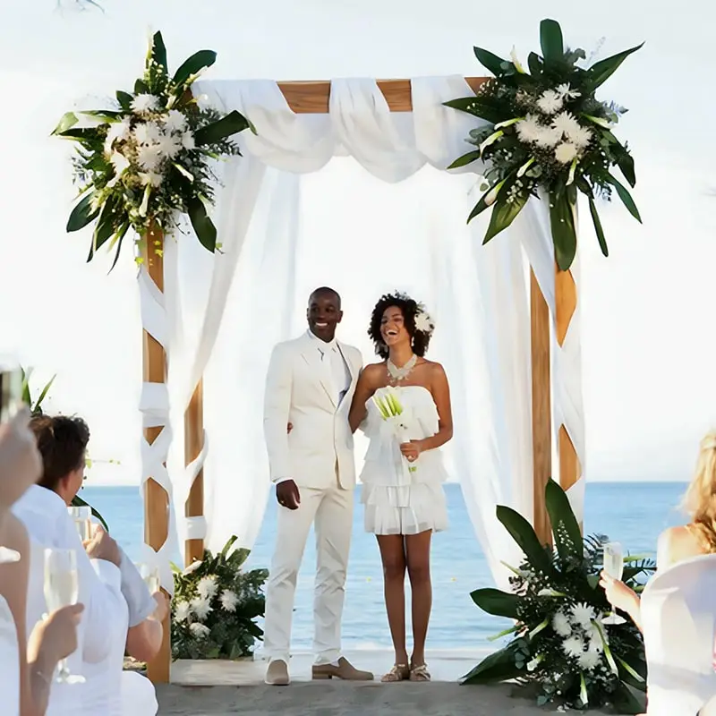 A couple getting married under an arch on the beach.