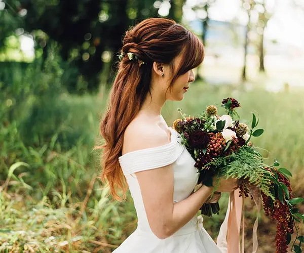 A woman holding flowers in her hand and wearing a white dress.