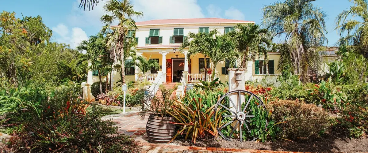 A large house with many plants in front of it.