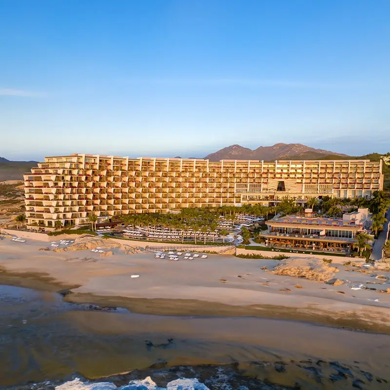 A large building on the beach with mountains in the background.