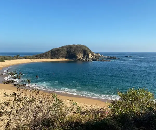 A beach with people on it and the ocean in front of them.