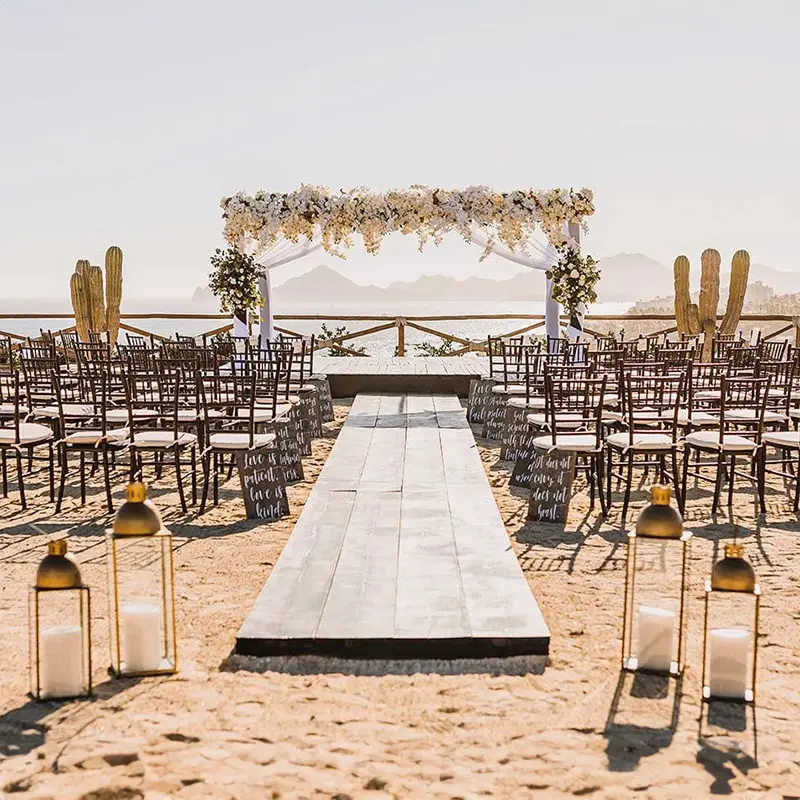 A wedding ceremony on the beach with chairs and lanterns.