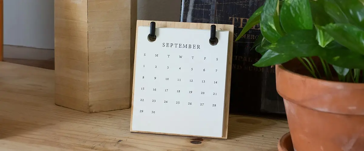 A calendar sitting on top of a wooden table.