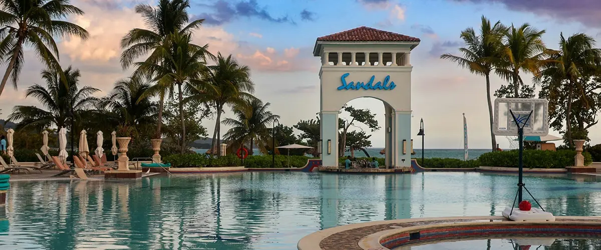 A large pool with palm trees and a resort sign.