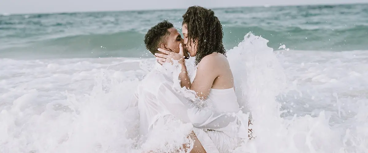 A man and woman kissing on the beach