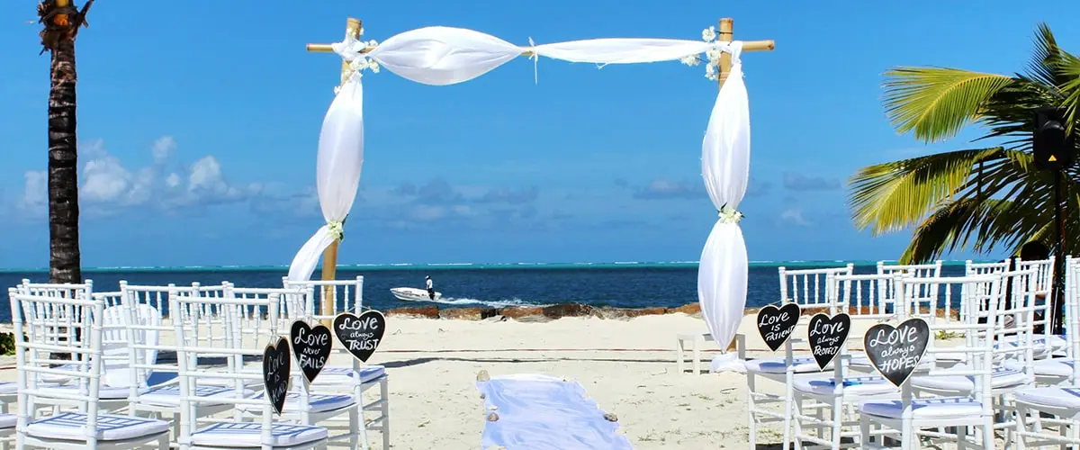 A beach with chairs and a wedding arch