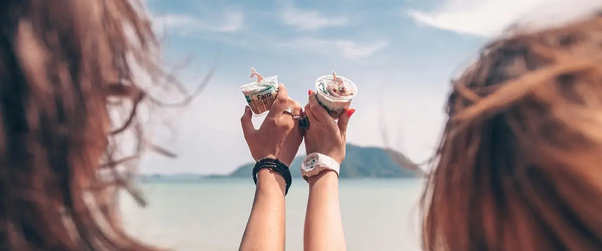 Two hands holding a sandwich in front of the ocean.