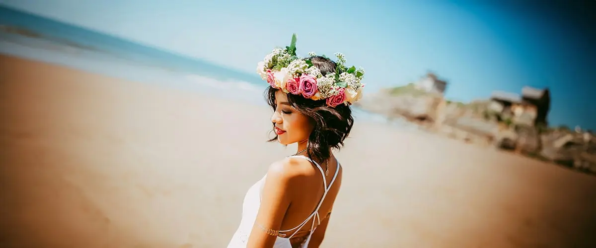 A woman with flowers in her hair on the beach.