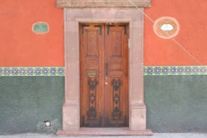 A door with two wooden doors and a brick wall.