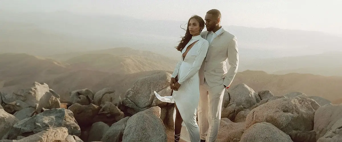 A man and woman standing on top of a mountain.