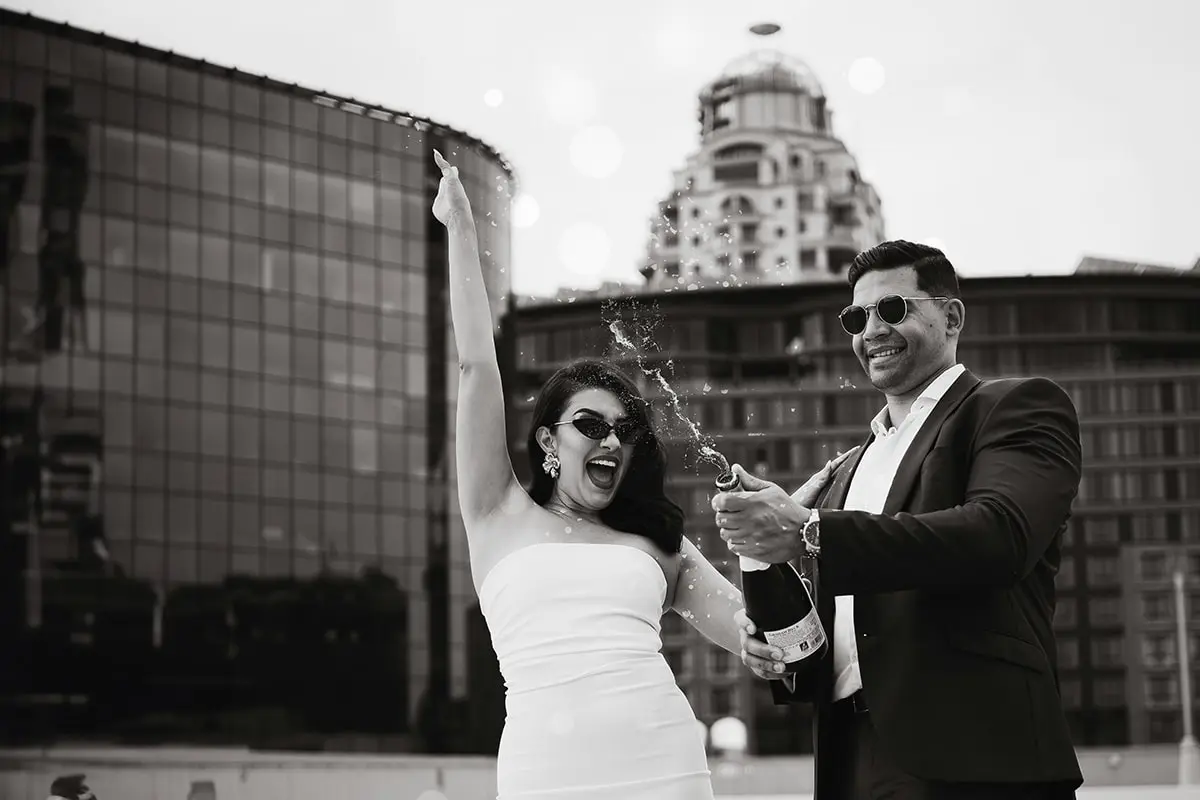 A man and woman holding up their arms in front of a building.