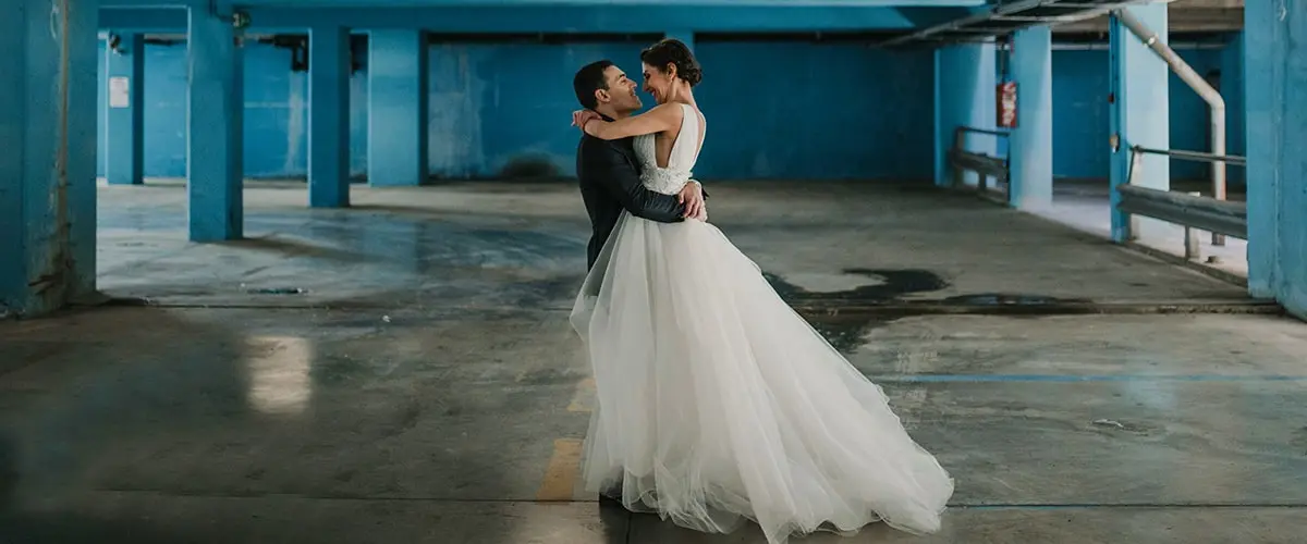 A man and woman in wedding dress embracing.