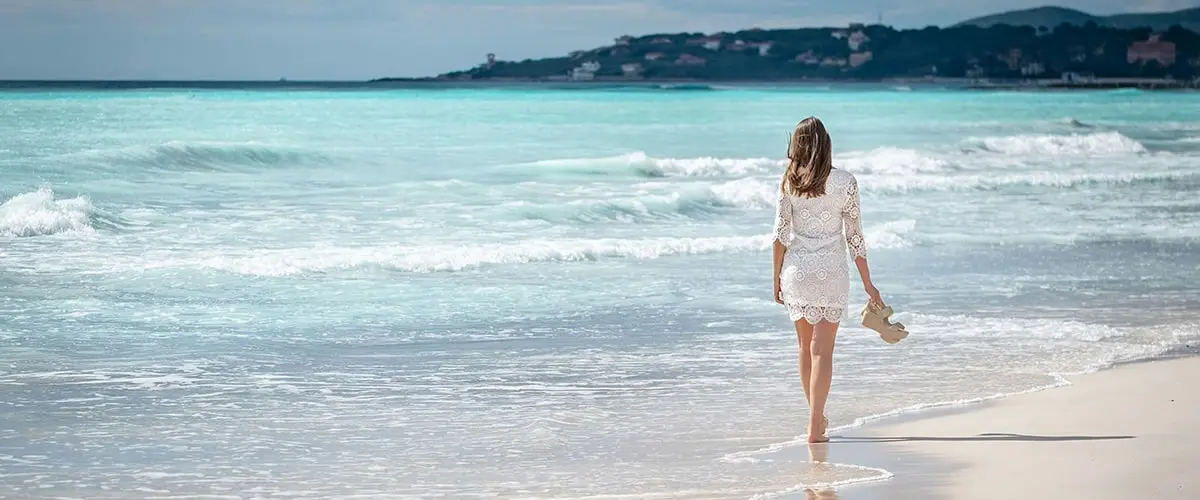 A woman walking on the beach in front of the ocean.