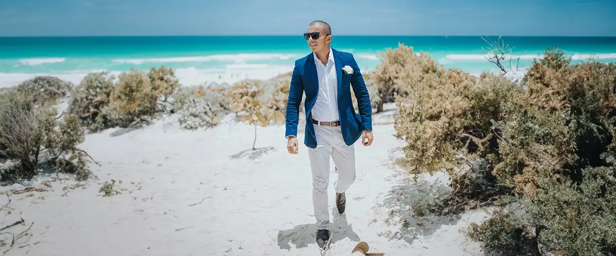 A man in a blue jacket walking on the beach.